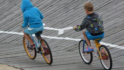 Chlapci jezdí po oválu na dětských kolech